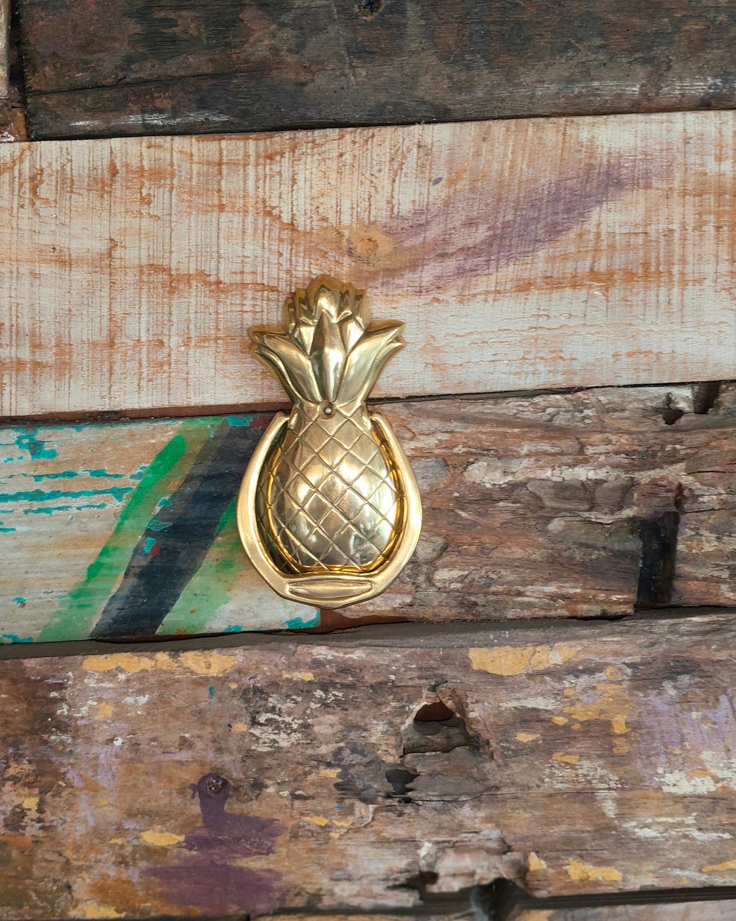 Gold pineapple-shaped door knocker on a rustic wooden door